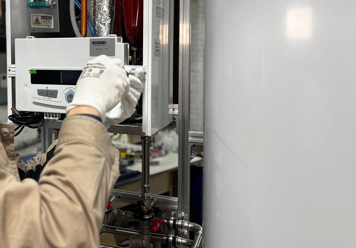 Technician installing or repairing a heating system in an indoor workshop setting.